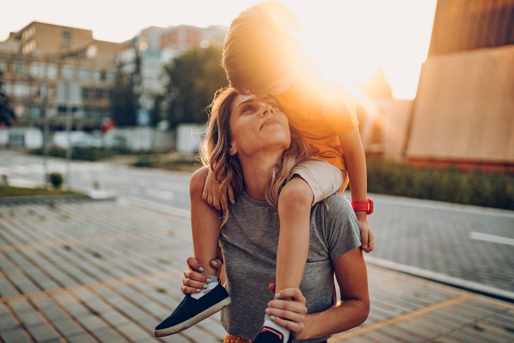 Mother and son playing outdoors, having fun and toothy smile